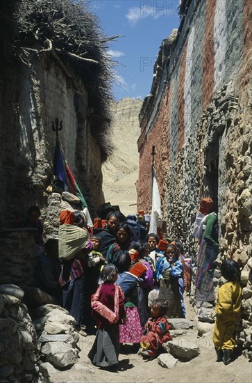 NEPAL, Mustang, Ghemi, People carry sacred texts through narrow street for the Lok Khor festival when prayers and offerings are made to ensure good harvests and protection for the home.