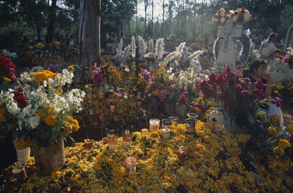 MEXICO, Michoacan State, Patzcuaro, Graves in Tzurumutaro cemetery decorated with candles marigold petals orchids and other flowers for Day of the Dead celebrations.
