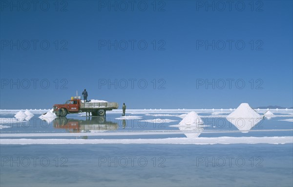 BOLIVIA, Uyuni, Salar de Uyuni, View over the white salt flats with salt piled up ready for collection by truck
