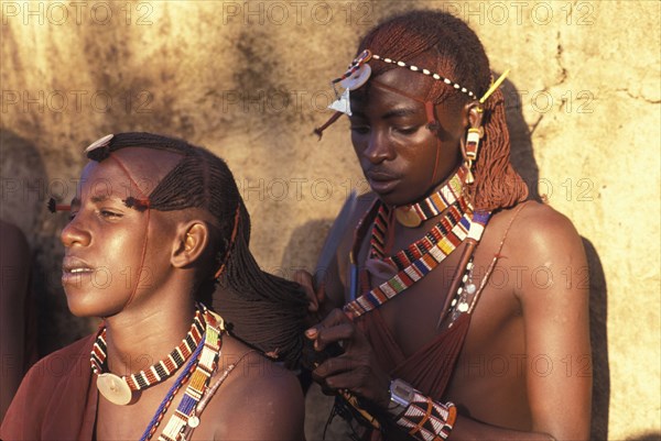 KENYA, , Maasai Moran platt each others hair prior to an initiation ceremony that will take them into manhood. The Moran live in age sets being brought up together like brothers.