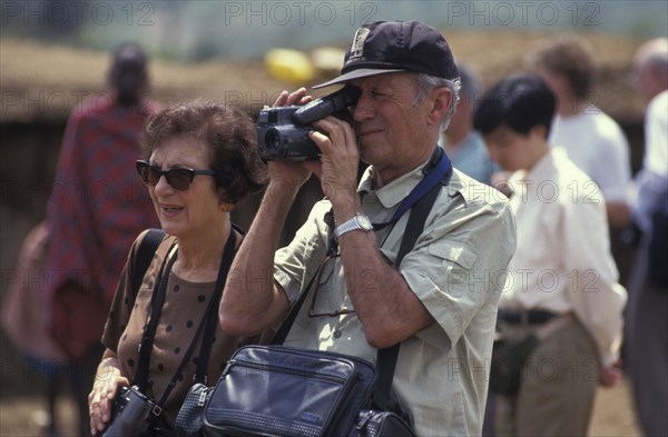 KENYA, , An American tourist films in a cultural manyatta set up to interface the Maasai directly with tourists.