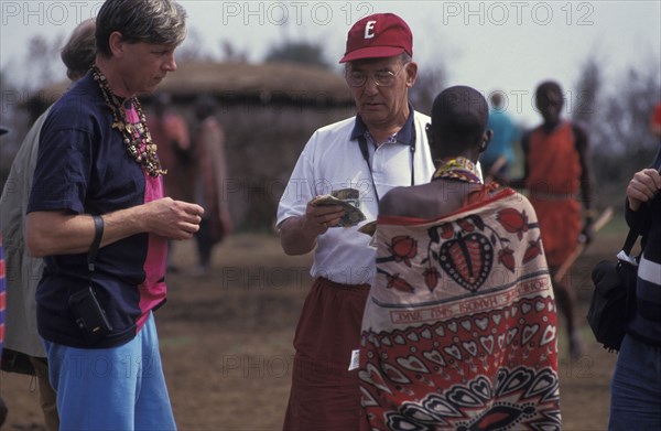 KENYA, , An American tourist haggles with a Maasai woman in a cultural manyatta set up to interface the Maasai directly with tourists.