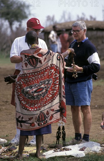 KENYA, , An American tourist haggles with a Maasai woman in a cultural manyatta set up to interface the Maasai directly with tourists.