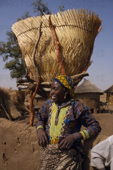 BURKINA FASO, Bisaland, Sigue Voisin Village, Girl standing below Grain store raised on stilts made from tree branches