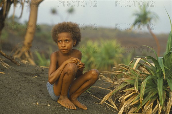 PACIFIC ISLANDS, Melanesia, Vanuatu, Tanna Island. Ni Vanuatu child sitting on volcanic sand.