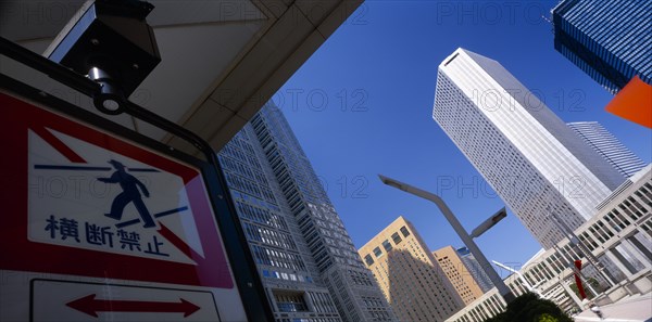 JAPAN, Honshu, Tokyo, West Shinjuku District. Angled view looking toward the multi storey Tokyo Metropolitan Government Offices seen from tunnel with pedestrian crossing sign in the foreground