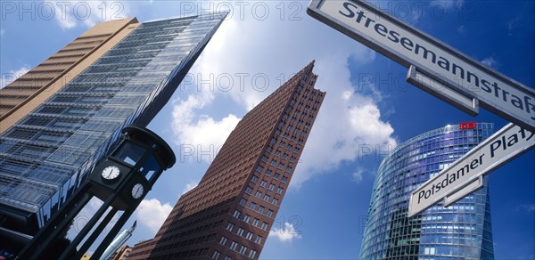 GERMANY, Berlin, Angled view of the city skyscrapers and clock with a sign post for Potsdamer Platz and Stresemannstrass in the foreground