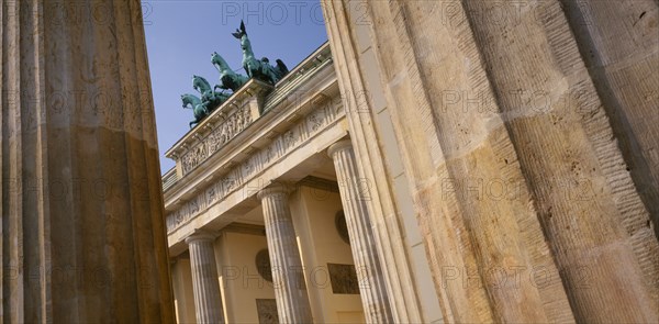 GERMANY, Berlin, Brandenburg Gate. Angled view looking up through pillars toward the crowning statues