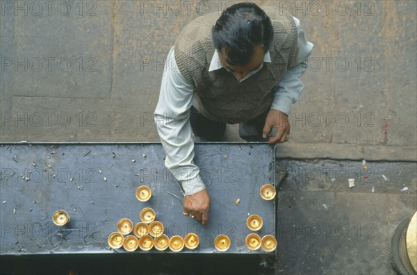 NEPAL, Patan, Looking down on man lighting butterwick candles at the Hiranyavarna Mahavihara Golden Temple