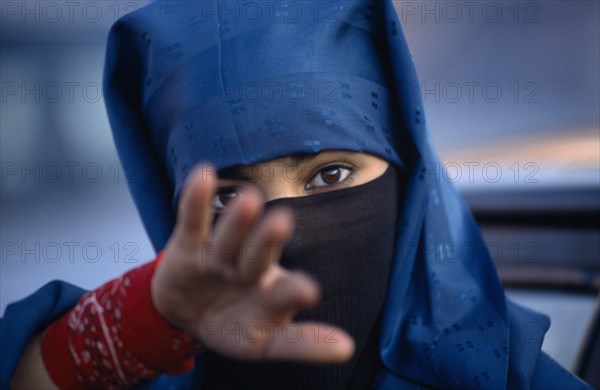 MOROCCO, Marrakech, Portrait of young veiled woman reaching towards camera possibly to stop photograph being taken.