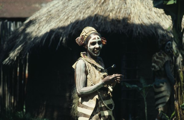 KENYA, Tribal People, Portrait of Kikuya tribeswoman wearing traditional jewellery and body paint standing outside hut.