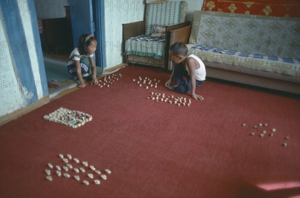 MONGOLIA, Children, Playing, Domestic interior with children playing game using knuckle bones to create herds of animals.