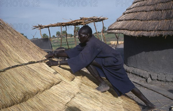 SUDAN, Tribal People, Dinka man thatching hut in cattle camp.