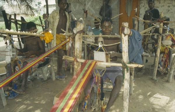 GHANA, Ashanti Region, Kumasi, Weaver at hand loom prodcungin traditional multi coloured Kente cloth