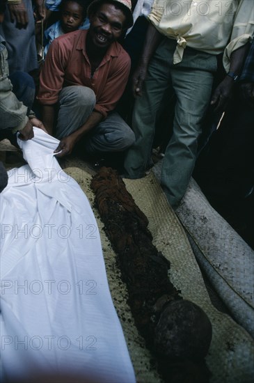MADAGASCAR, Festivities, Merina Famadihana or bone turning festival.  Man with disinterred remains of dead ancestor.