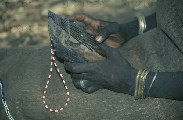 ETHIOPIA, Music, Cropped view of Mursi girl playing traditional thumb piano musical instrument.