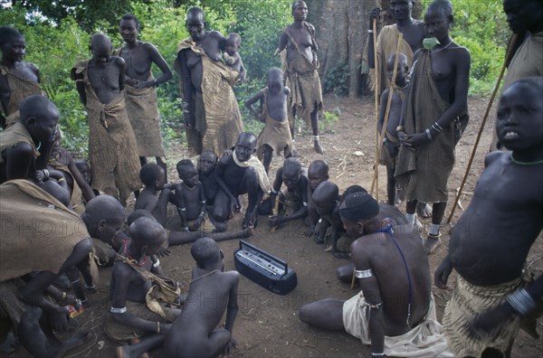 ETHIOPIA, Tribal People, Mursi tribe gathering around cassette player.