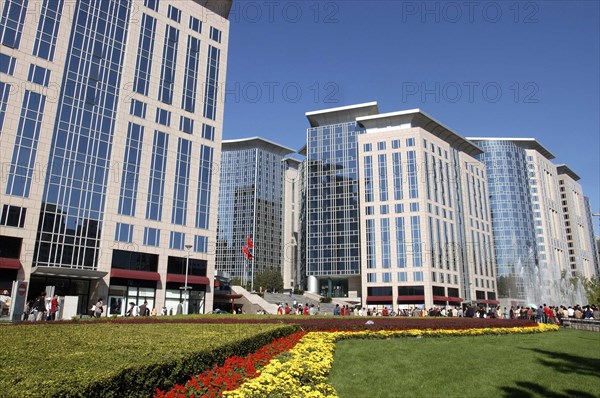 CHINA, Beijing, Modern city architecture with red and yellow flowerbeds in the foreground