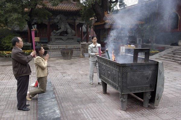 CHINA, Beijing, Lama Temple. People lighting incense during worship in the Temple courtyard