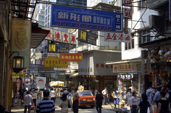 HONG KONG, General, View along busy city street with passing traffic and pedestrians and overhead advertising banners