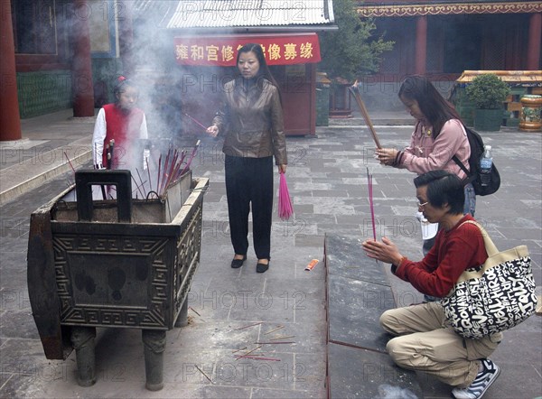 CHINA, Beijing, Lama Temple. People lighting incense during worship in the Temple courtyard
