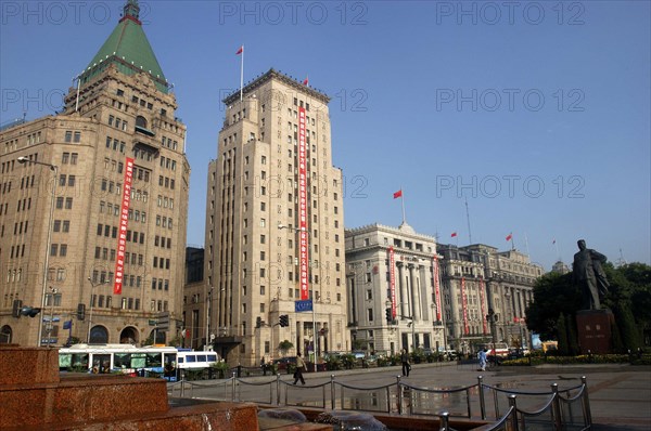 CHINA, Shanghai, The Bund aka Zhong Shan Road. 1930s style waterfront architecture including the Peace Hotel and the Bank of China with statue of Mao and fountain in the foreground