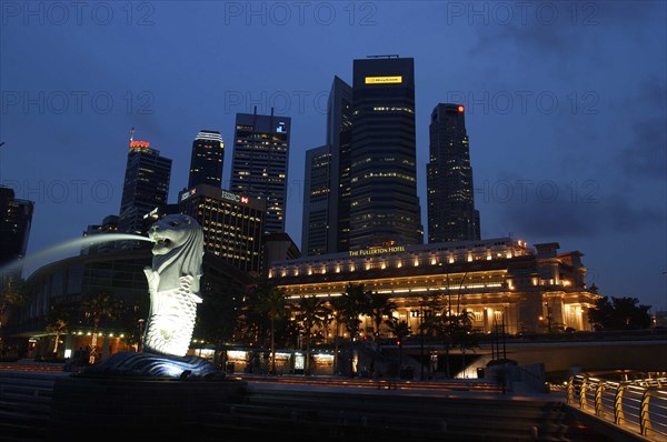SINGAPORE, , Merlion statue spouting water illuminated against a night time city skyline