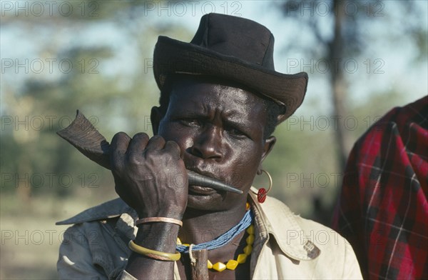 UGANDA, Karamoja  , Portrait of a Dodoth Karamojong warrior blowing an antelope horn to call a meeting of other warriors and elders.