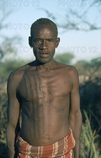 UGANDA, Karamoja, Tribal Poeple, Portrait of Karamojong Mathenico clan warrior.  Scarification indicates the number of enemies killed.