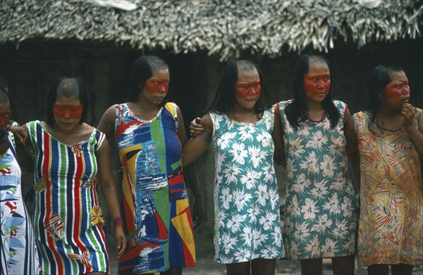 BRAZIL, Amazonas, Xingu Park, Xikrin Indian women with the tops of their heads shaved and their faces painted with red urucu juice but wearing western style dress.
