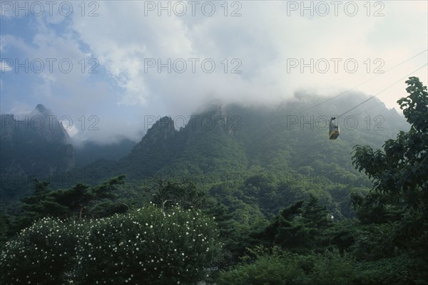 SOUTH KOREA, Kangwon, Soraksan National Park, Sorak Mountains.  Cable car to peak of Chipsonbong mountain wreathed in cloud with lush vegetation below.