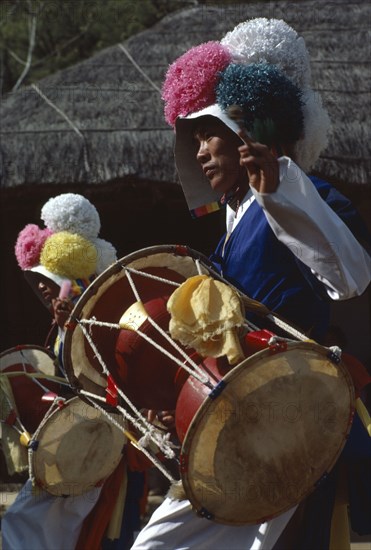 SOUTH KOREA, Arts, Dance, Farmers Dance.  Young man wearing paper flowered hat and playing drum.