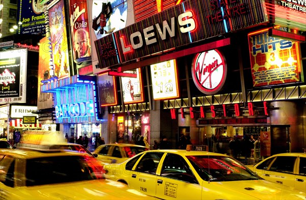 USA, New York State, New York City, Times Square illuminated at night with passing yellow taxi cabs