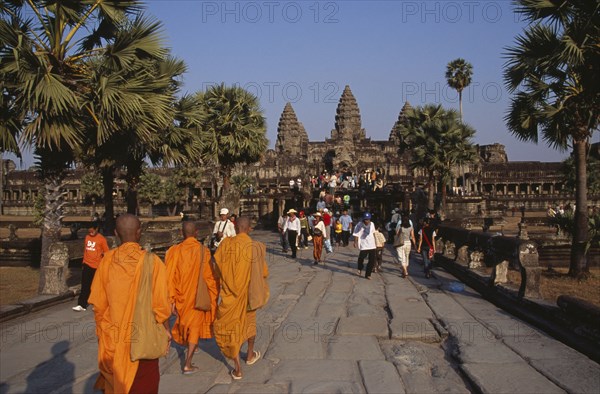 CAMBODIA, Siem Reap Province, Angkor Wat, Buddhist monks and tourists during Chinese New Year on tree lined stone causeway leading to temple complex.