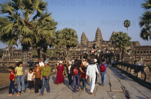 CAMBODIA, Siem Reap Province, Angkor Wat, Tourists on tree lined stone causeway leading to temple complex.  Many Cambodians visiting during Chinese New Year.