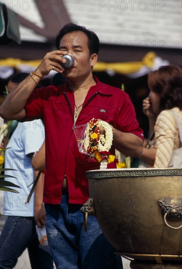 THAILAND, South, Bangkok, Wat Meuang the City pillar the most important animist shrine in Bangkok with male devotee drinking votive water