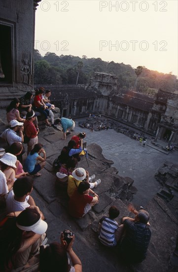 CAMBODIA, Siem Reap Province, Angkor Wat, Tourists with cameras watching the sunset from the central sanctuary on the upper level.
