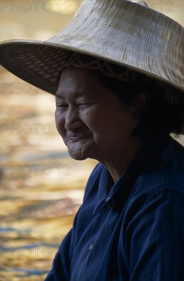 THAILAND, South, Bangkok, Damnoen Saduak Floating Market portrait of an old female vendor wearing a straw hat