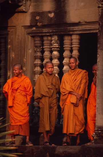CAMBODIA, Siem Reap Province, Angkor Wat, Buddhist monks standing in front of window of upper level gallery.