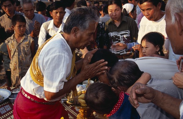 CAMBODIA, Siem Reap, Angkor Wat, Shaman at ceremony giving blessings by spraying water from his mouth onto devotees heads