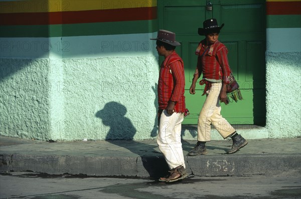 GUATEMALA, Western Highlands, Mayan Indian men from the Sierra los Cuchumatanes at the busy market town of Huehuetanango walking past green painted walls.
