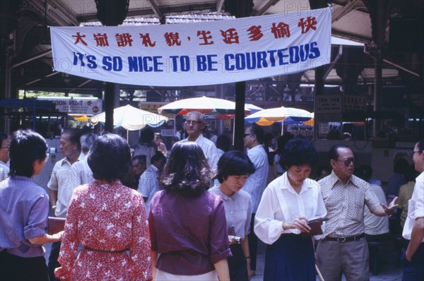 SINGAPORE, General, Street scene with mixed crowd below government banner stating Its So Nice To Be Courteous.