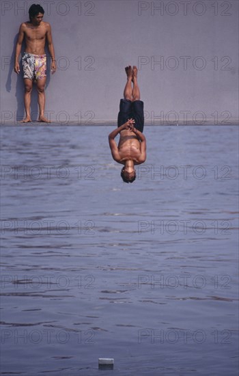 PHILIPPINES, Manila, Boys jumping off the Metrorail Bridge into the filthy Passig river.