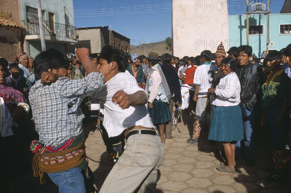 BOLIVIA, Potosi, Macha, Traditional Tinku fighting festival. Crowds watching two young men fighting in street.