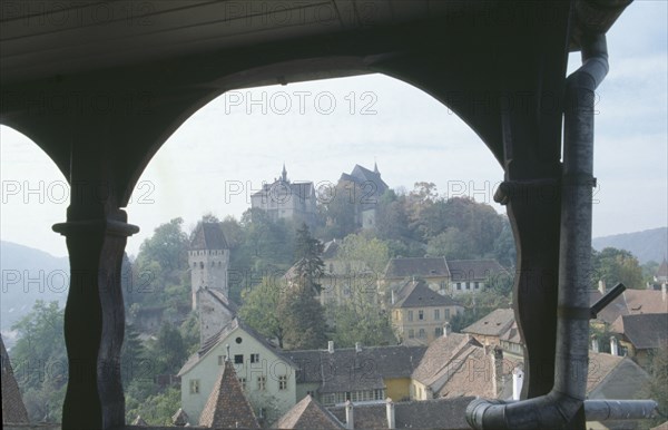 ROMANIA, Transylvania, Mures, Sighisoara.  View of town rooftops framed by archway.  Famous as being the birthplace of Vlad Tepes or Dracula.