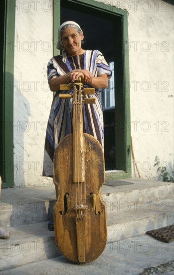 ROMANIA, Transylvania, Gimes Village, "Elderly woman with a gardon, a traditional cello like instrument played by hitting the strings with a small stick."