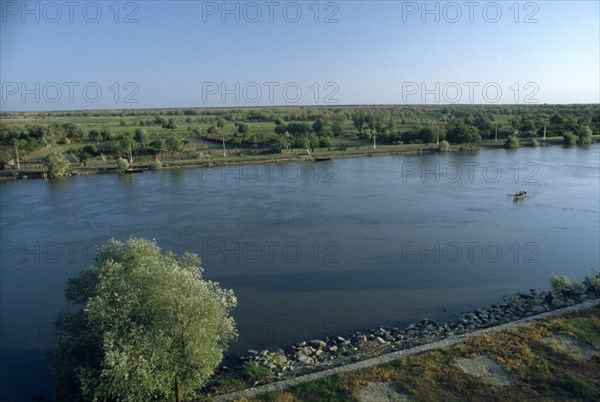 ROMANIA, Danube Delta, "Small rowing boat on the River Danube through flat, tree covered landscape."