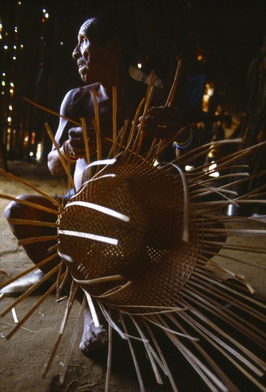 COLOMBIA, Amazonas, Santa Isabel, Macuna man weaving thin wooden strips to make basket.