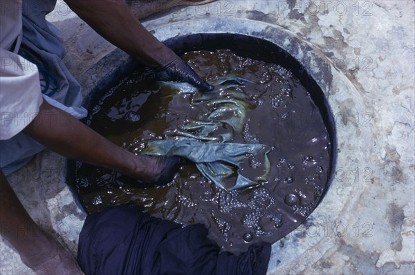 NIGERIA, Kano, Cropped view of worker and indigo dye pit.  To achieve a  dark colour requires repeated immersions.