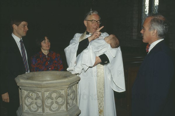 ENGLAND, Yorkshire, Religion, Church of England baptism. Priest makes sign of the cross on the babys forehead with holy water from font.